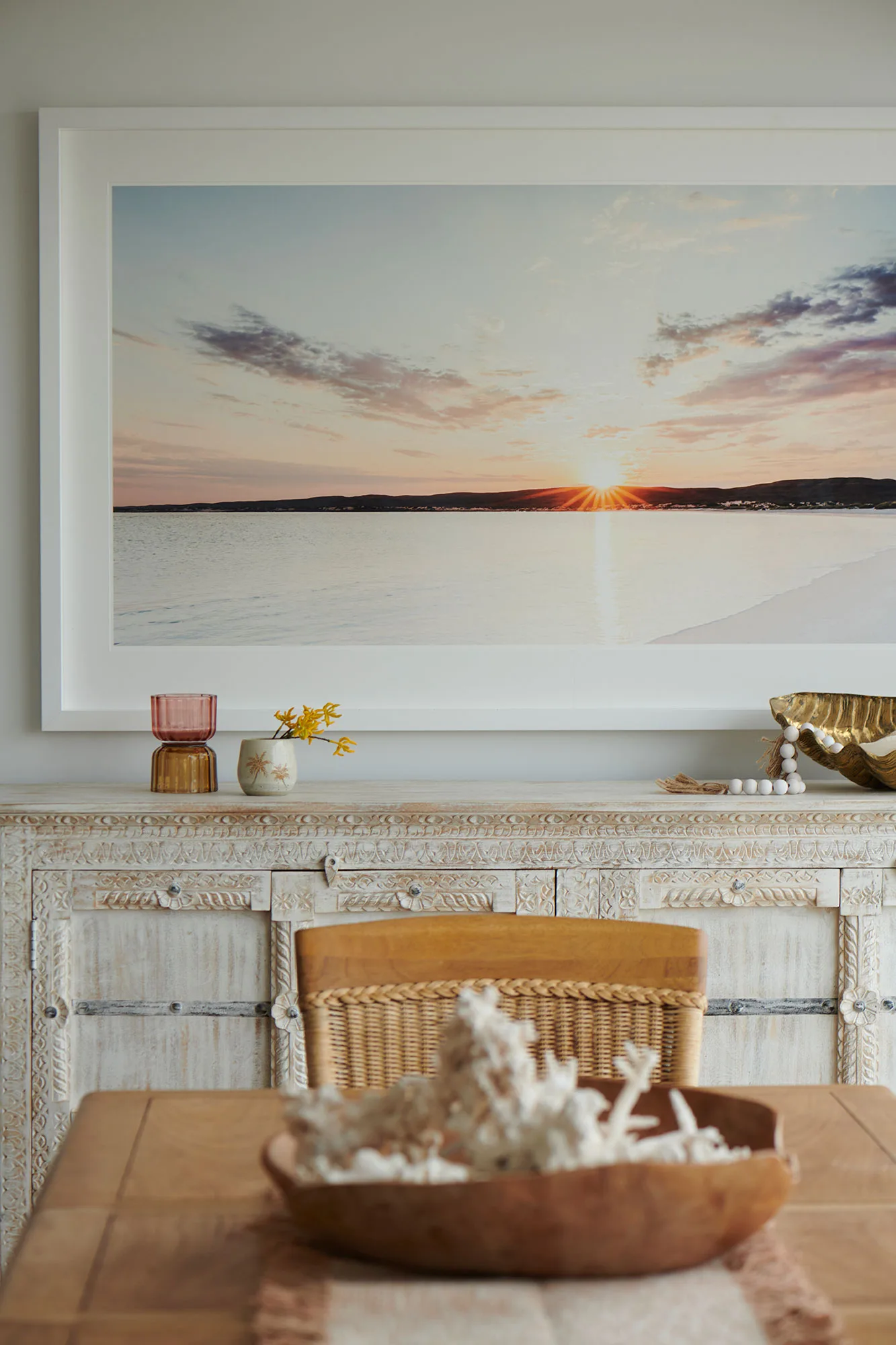 Exmouth I home — dining detail with carved sideboard, framed sunset photograph and brass clam shell