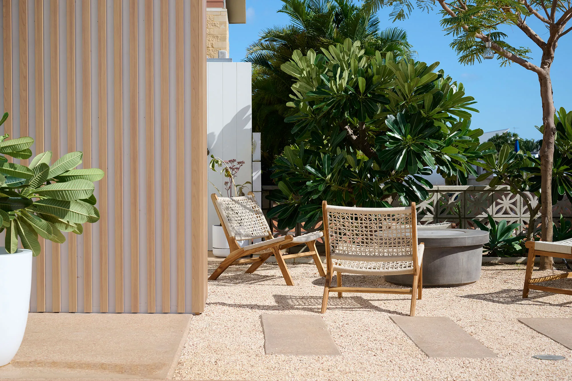 Exmouth I home — outdoor courtyard with timber batten wall, woven chairs and concrete fire pit