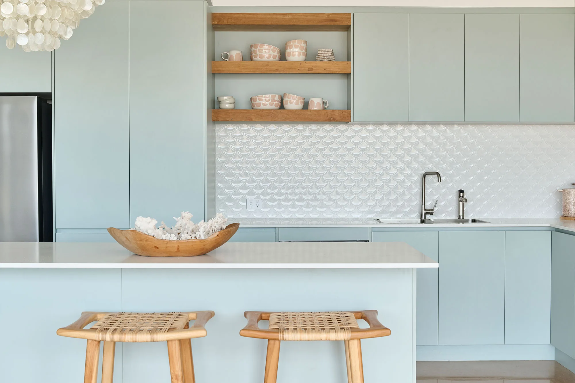 Exmouth I home — kitchen with mint green cabinetry, scalloped tile splashback and woven stools